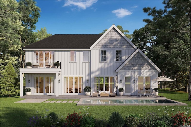 rear view of house with a yard, a balcony, and a patio