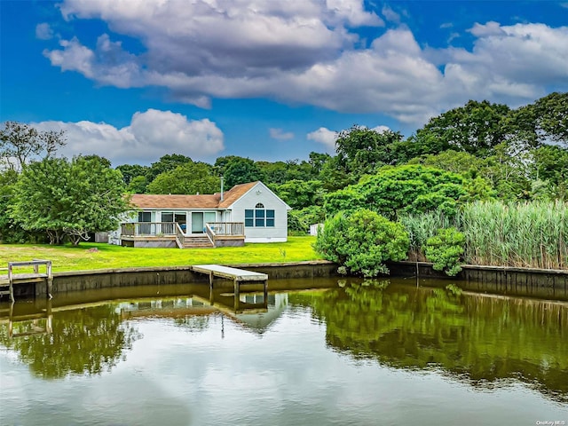 rear view of property featuring a lawn and a deck with water view