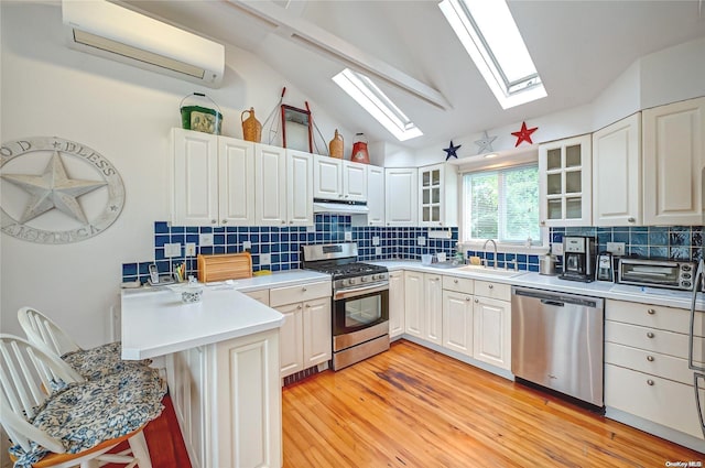 4 Landing Ln, Southampton, NY 11968 - kitchen with appliances with stainless steel finishes, a skylight, a sink, a wall mounted AC, and vaulted ceiling