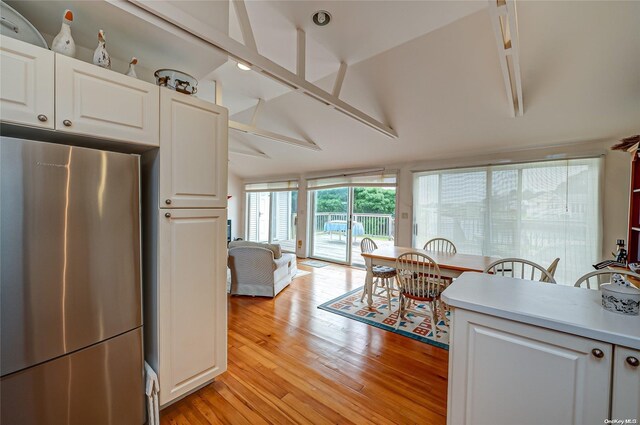 4 Landing Ln, Southampton, NY 11968 - kitchen with freestanding refrigerator, light wood-style flooring, white cabinetry, light countertops, and lofted ceiling