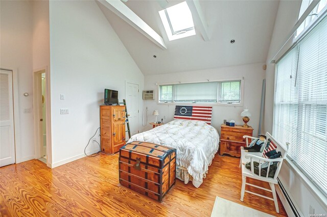 4 Landing Ln, Southampton, NY 11968 - bedroom with high vaulted ceiling, a skylight, light wood finished floors, a wall mounted AC, and baseboard heating