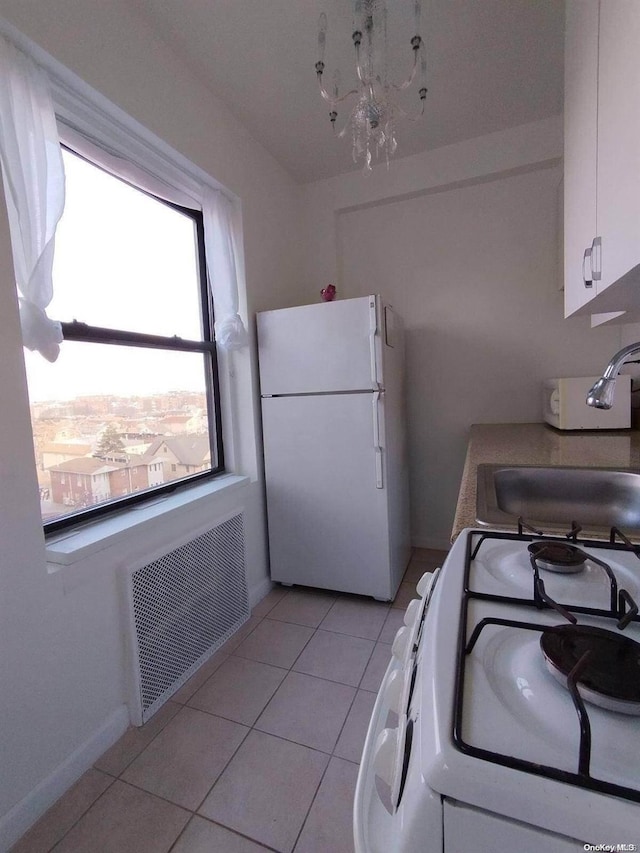 kitchen with sink, white cabinets, white appliances, and light tile patterned floors