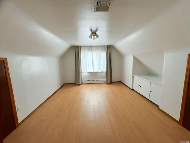 bonus room featuring a baseboard heating unit, light wood-type flooring, and lofted ceiling