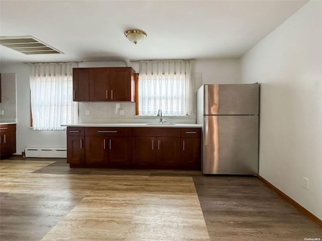 kitchen with stainless steel refrigerator, hardwood / wood-style floors, and a healthy amount of sunlight