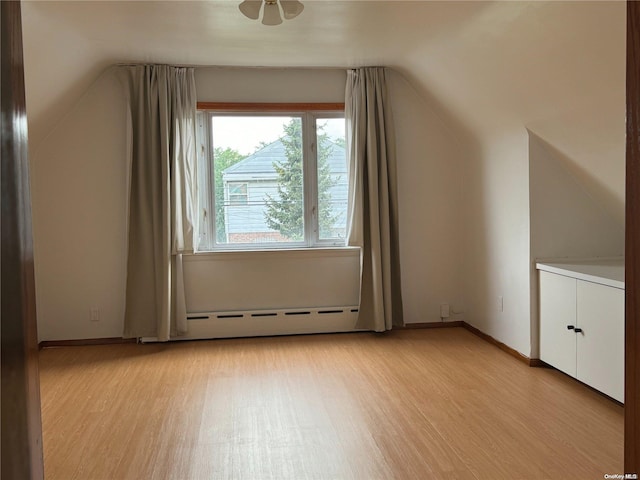 additional living space with light hardwood / wood-style flooring, vaulted ceiling, and a baseboard radiator