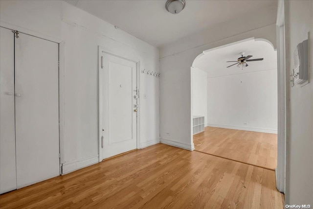 entrance foyer with arched walkways, visible vents, a ceiling fan, and wood finished floors