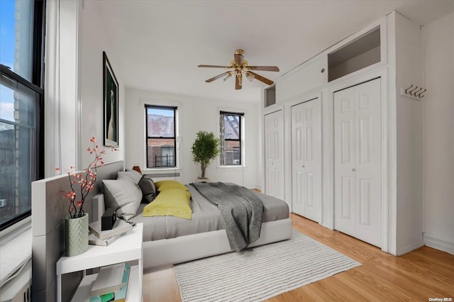 bedroom featuring multiple closets, light wood-type flooring, and ceiling fan