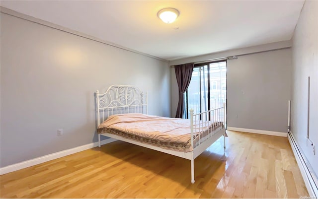 bedroom with hardwood / wood-style floors and a baseboard heating unit