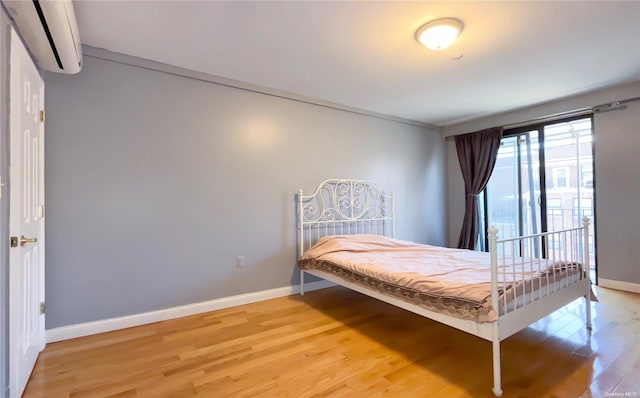 bedroom with light wood-type flooring and a wall unit AC