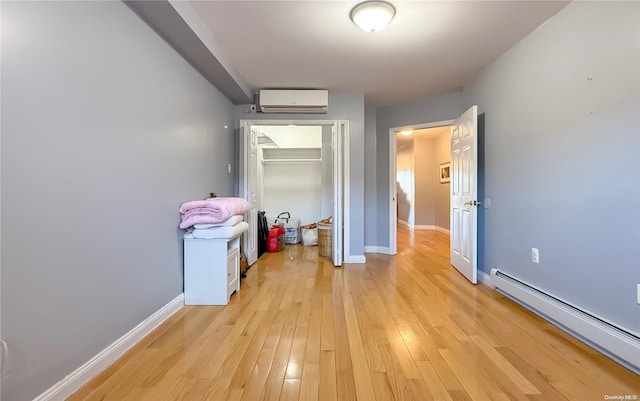 hall with light hardwood / wood-style floors, baseboard heating, and a wall unit AC