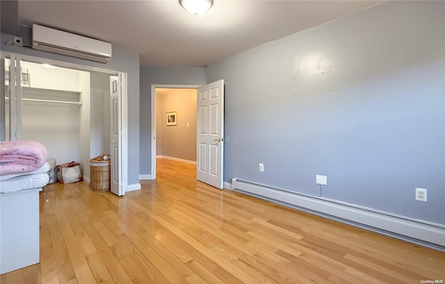 unfurnished bedroom featuring a wall mounted air conditioner, a baseboard radiator, a closet, and light hardwood / wood-style floors