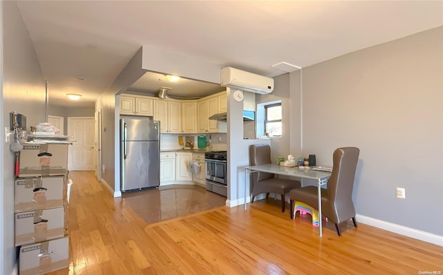 kitchen featuring cream cabinetry, stainless steel appliances, light hardwood / wood-style flooring, and a wall mounted AC