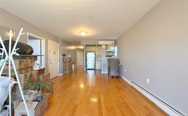 corridor with baseboard heating, light hardwood / wood-style flooring, and an AC wall unit