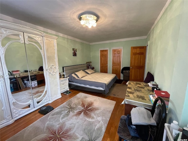 bedroom featuring multiple closets, dark wood-type flooring, and ornamental molding