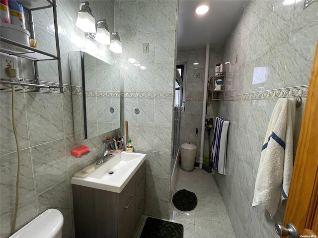 bathroom with vanity, toilet, and tile walls