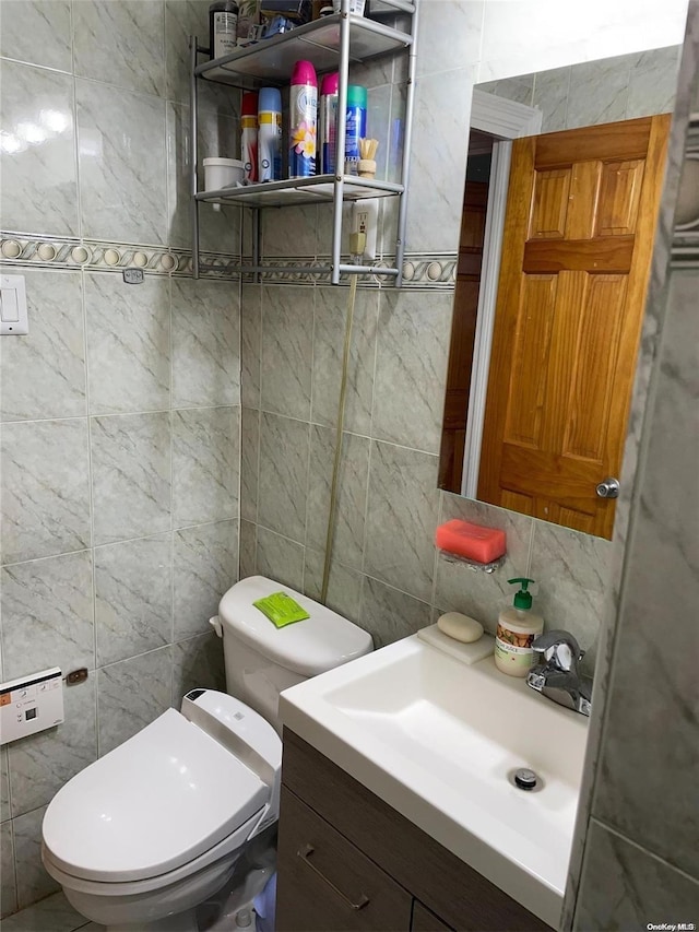 bathroom with vanity, toilet, and tile walls