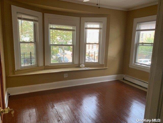 spare room with dark hardwood / wood-style flooring, a baseboard radiator, and ceiling fan