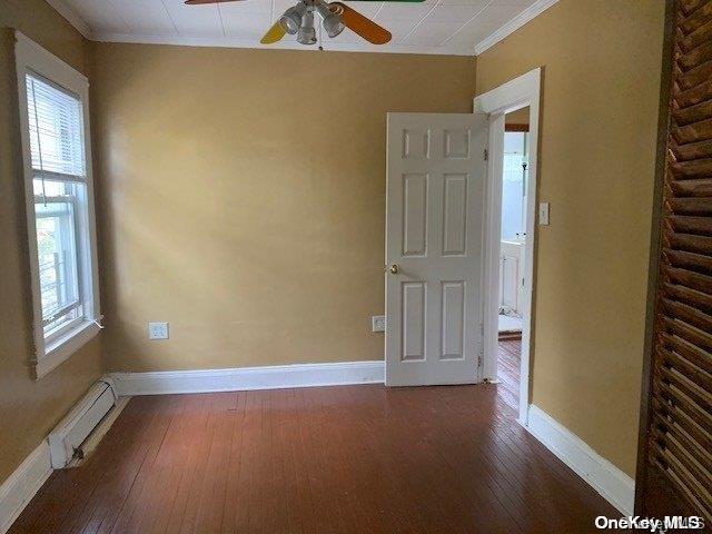 spare room featuring crown molding, dark hardwood / wood-style flooring, ceiling fan, and a baseboard radiator