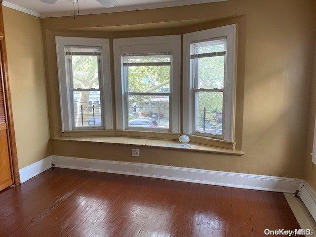 spare room with hardwood / wood-style floors, ceiling fan, a wealth of natural light, and a baseboard radiator