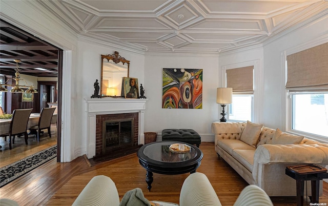 living room with a fireplace, hardwood / wood-style flooring, ornamental molding, and coffered ceiling