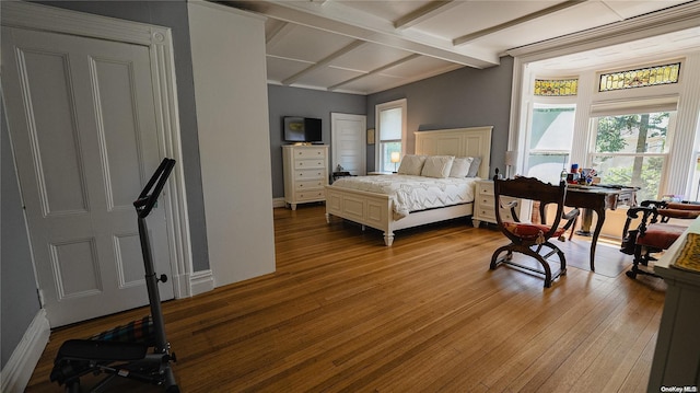 bedroom with beamed ceiling and light hardwood / wood-style flooring