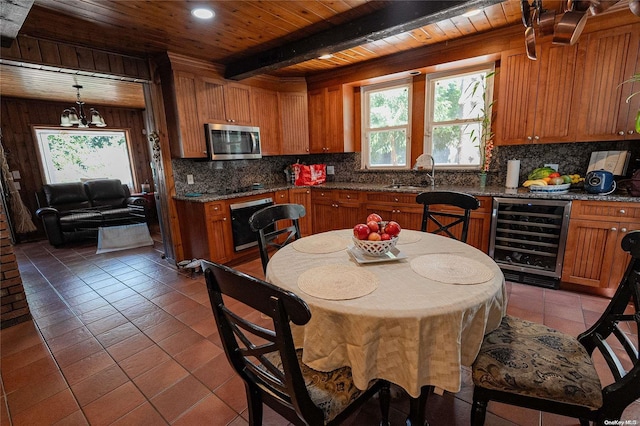 kitchen featuring beverage cooler, an inviting chandelier, beamed ceiling, tile patterned floors, and pendant lighting