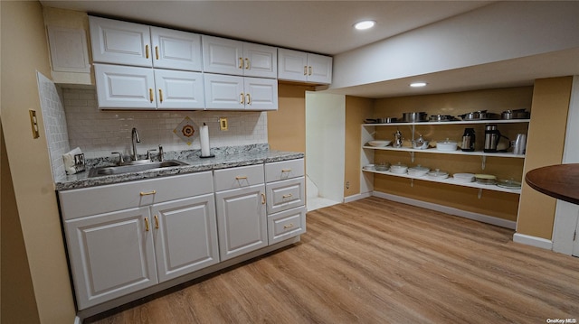 kitchen with white cabinets, light wood-type flooring, and sink