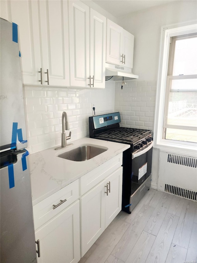 kitchen featuring radiator, a wealth of natural light, sink, and stainless steel gas range