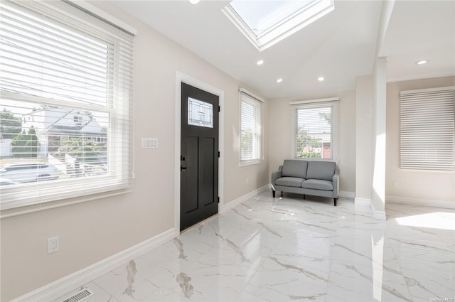 foyer entrance with lofted ceiling with skylight and a healthy amount of sunlight