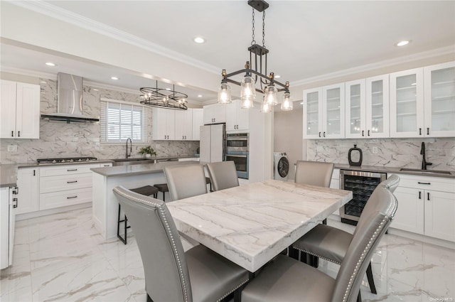 kitchen featuring pendant lighting, wall chimney range hood, a kitchen island, a kitchen bar, and beverage cooler