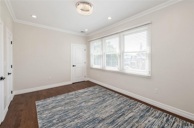 empty room with dark hardwood / wood-style flooring, crown molding, and a chandelier