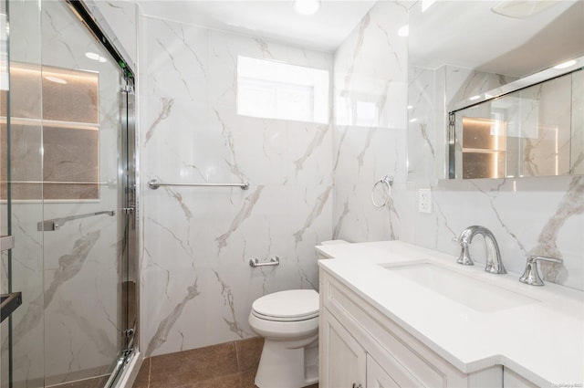 bathroom featuring toilet, decorative backsplash, a shower with door, vanity, and tile walls