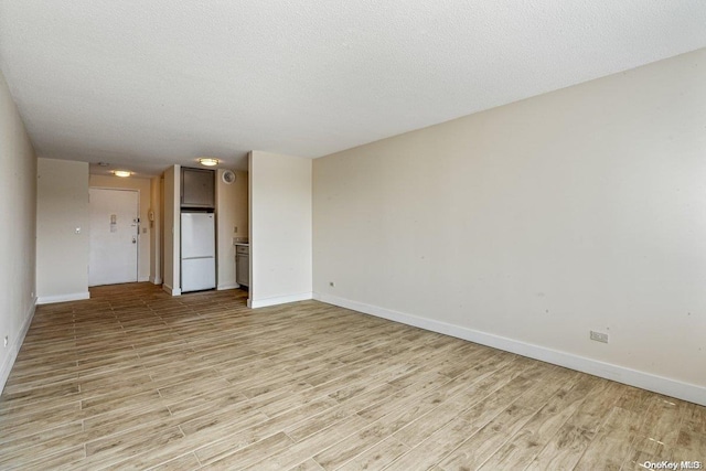 unfurnished room featuring a textured ceiling and light hardwood / wood-style flooring