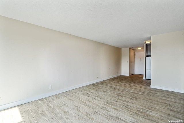 spare room with a textured ceiling and light hardwood / wood-style floors