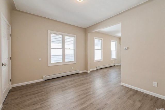 empty room with light hardwood / wood-style flooring and a baseboard heating unit