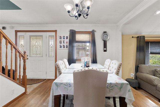 dining area with a notable chandelier, light wood-type flooring, and crown molding