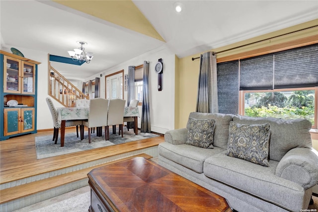 living room featuring vaulted ceiling, wood-type flooring, and a chandelier