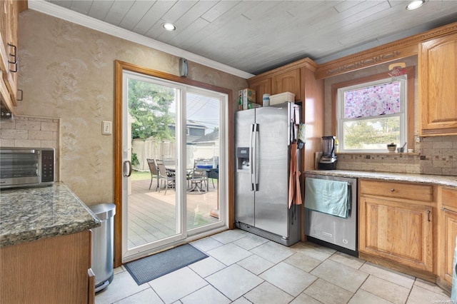 kitchen featuring light tile patterned flooring, ornamental molding, appliances with stainless steel finishes, and dark stone counters