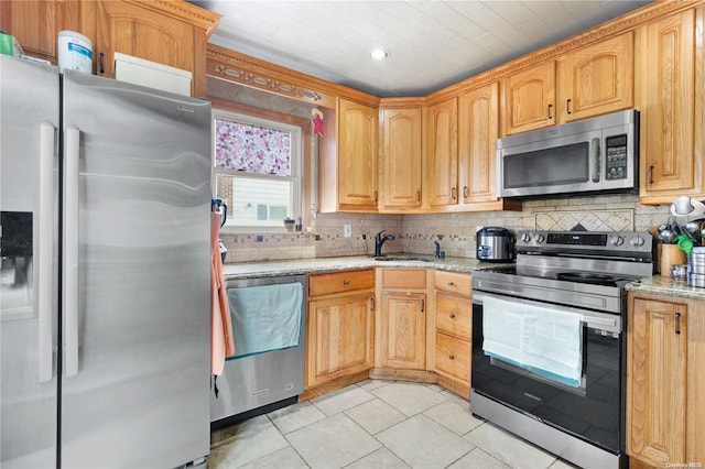 kitchen featuring tasteful backsplash, light stone counters, light tile patterned floors, and appliances with stainless steel finishes