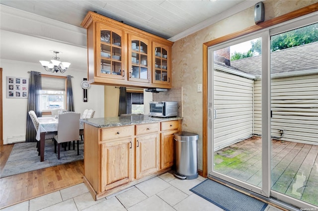 kitchen with light hardwood / wood-style flooring, a notable chandelier, crown molding, and light stone counters