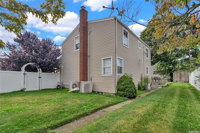 view of side of property featuring a lawn, ac unit, and a storage shed