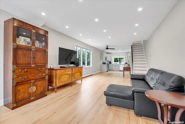 living room featuring ceiling fan, light hardwood / wood-style floors, and a baseboard heating unit