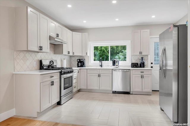 kitchen with appliances with stainless steel finishes, tasteful backsplash, white cabinetry, and sink