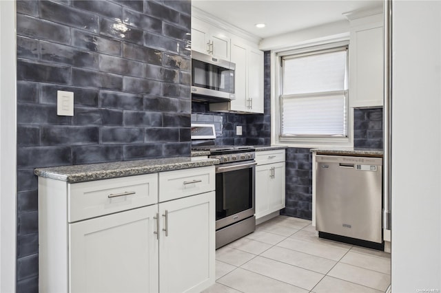 kitchen with white cabinets, appliances with stainless steel finishes, backsplash, and light tile patterned floors