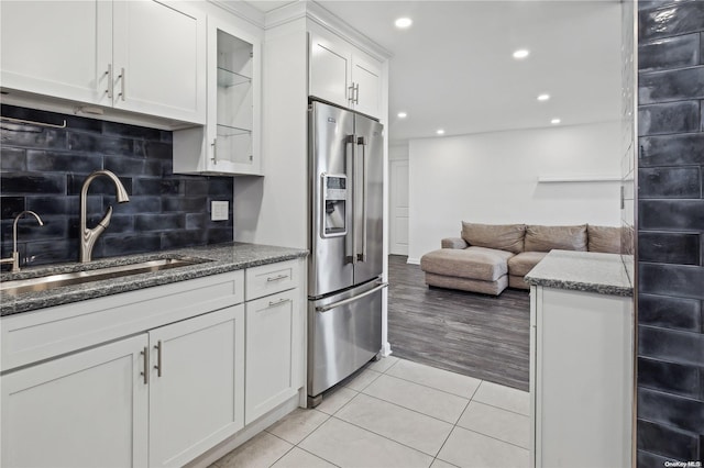 kitchen with white cabinets, stainless steel fridge with ice dispenser, sink, and light hardwood / wood-style flooring