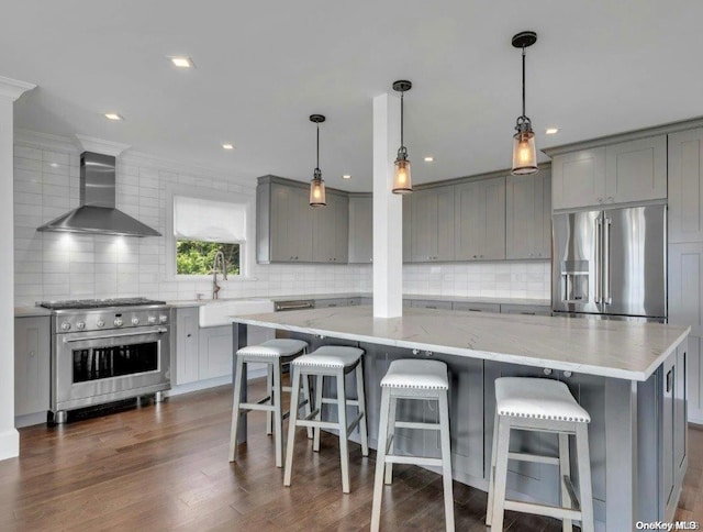 kitchen featuring a spacious island, high end appliances, wall chimney range hood, and dark wood-type flooring