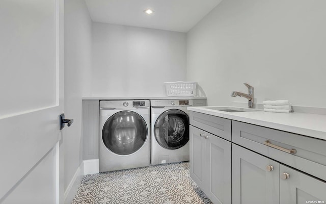 laundry area featuring separate washer and dryer, sink, and cabinets