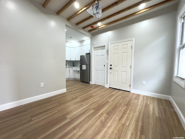 spare room with beamed ceiling and hardwood / wood-style flooring