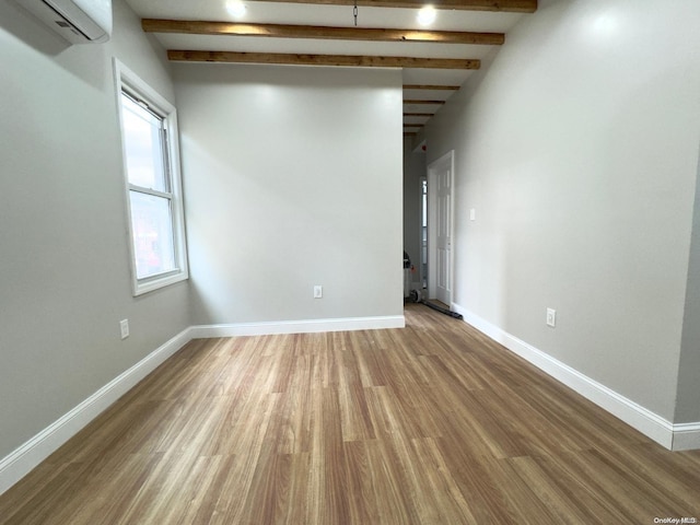 unfurnished room with wood-type flooring, an AC wall unit, and beam ceiling