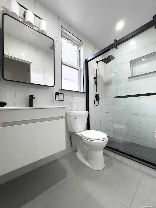 bathroom featuring tile patterned floors, an enclosed shower, vanity, tile walls, and toilet